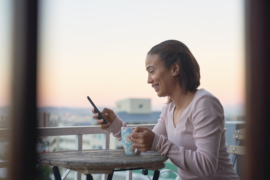 beautiful young woman with coffee and phone outdoors on the bal