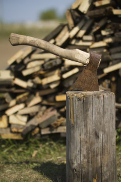 Old axe stuck in stump near woodpile