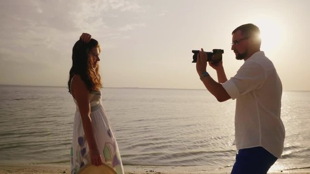 The husband takes pictures of his young wife on the beach. Happy holidays together