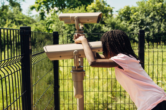 Black girl looking through binoculars at a forest preserve