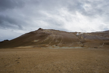 Fototapeta na wymiar Iceland - Brown volcanic mountains and ground and fumaroles at geothermal area hverir