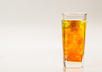 Orange food coloring diffuse in water inside glass with empty copyspace area for slogan or advertising text message, over isolated grey background