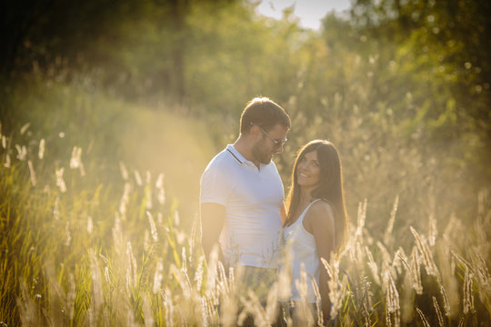 Beautiful loving couple walking toghether outdoor on the nature. Romantic dating in the summer sunset.