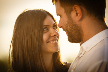 Portrait of a beautiful and young woman with brown hair who loves looking at his husband with a beard, the couple is on nature in the hot summer day