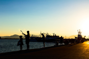 Silhouetted shot of a people fishing on pier at sunset
