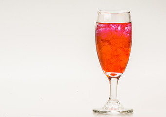 mixture of food coloring diffuse in water inside wine glass with empty copyspace area for slogan or advertising text message, over isolated grey background. 