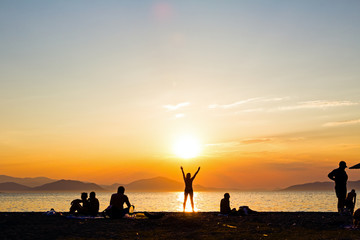 Fototapeta premium Silhouetted shot of sunset with people by the beach