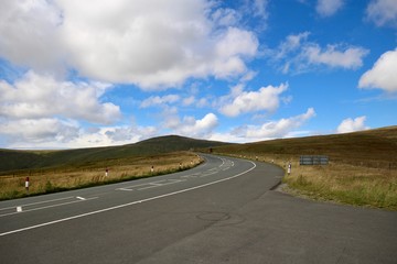 A sweeping bend on the mountain road against a bright blue sky on the Isle of Man