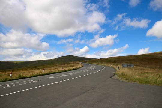 A sweeping bend on the mountain road against a bright blue sky on the Isle of Man