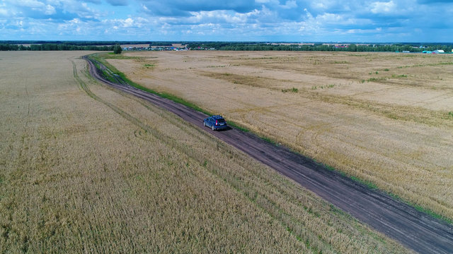 The car rides along the wheat fields. Beautiful landscape from the height. Photos from a height