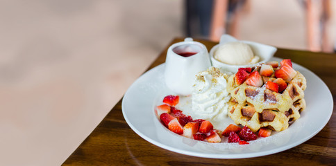 Waffle strawberry with vanilla ice cream on the table with blurry background inside coffee shop