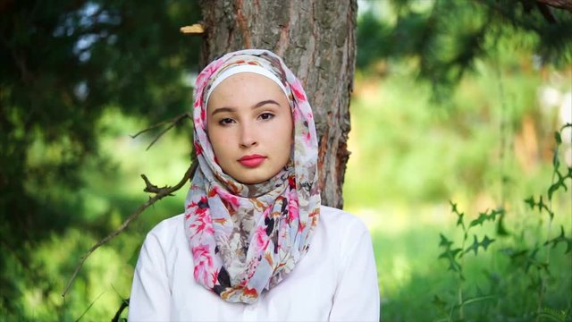 Pretty Muslim girl with faint smile. Outdoor portrait of a woman wearing bright hijab