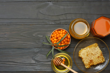 Sea buckthorn in wooden bowl, honey, Sea buckthorn juice on dark wooden table. top view with copy space