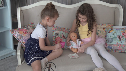 Little sister girls feed their doll