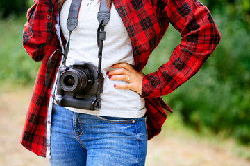 Female wearing plaid shirt holding the camera around her neck