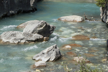 Detail of the glacial blue river water and rocks along the Tokumen River, Canada