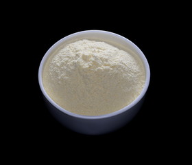 Pile corn flour in white bowl isolated on black background