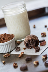 One Chocolate Truffle Surrounded by Chocolate Pieces and Pecans With Cocoa Powder and Milk