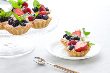 Mini tarts on the plate close up. Homemade dessert with delicious catalonian traditional cream and fresh berries