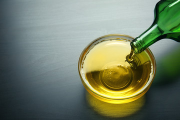 Pouring cooking oil into bowl on dark table
