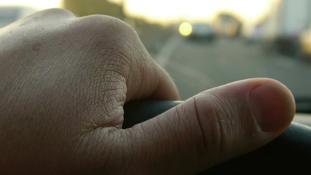 Driving at Sunset on the freeway. Traffic Jam. -Hand on steering wheel close up.
