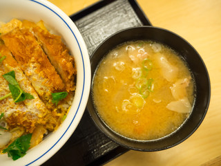 Traditional soup udon, in a black plate, on table. Japanese soup called Udon with deep fried shrimp or tempura. Soup with udon noodles and shrimps. original soup udon from Japan
