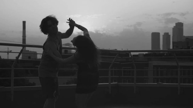 Silhouettes of young couple dancing on sunset