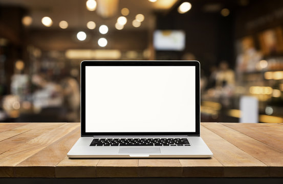 Modern computer,laptop with blank screen on table with blur cafe,restaurant background