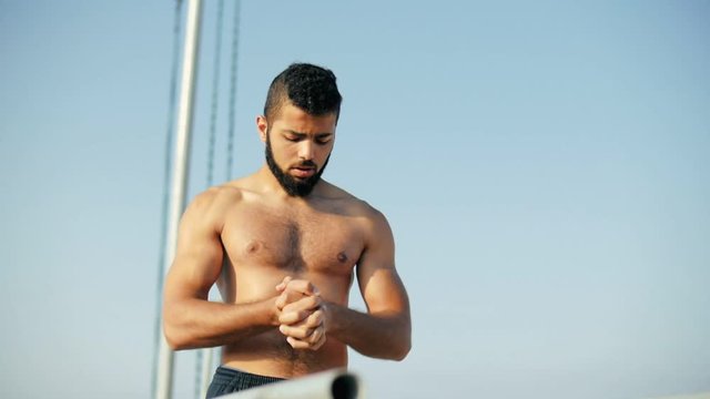 Sportsman doing warm up exercises with joint palms. Man pushing on uneven bars