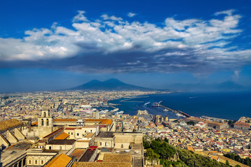 Fototapeta na wymiar Italy. Cityscape of Naples (UNESCO World Heritage Site) seen from Castle Sant'Elmo. There is Certosa e Museo di San Martino in the foreground and Mount Vesuvius in the background