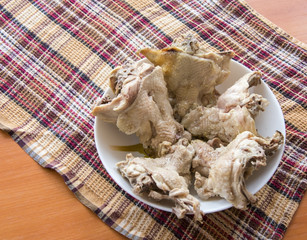 Boiled chicken backs in the plate on the wooden table top on a checkered kitchen towel