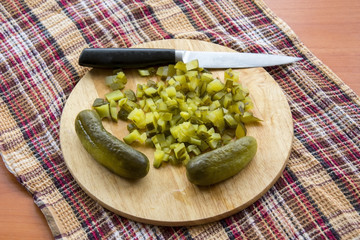 Finely chopped pickled cucumber on the board and a cutting knife