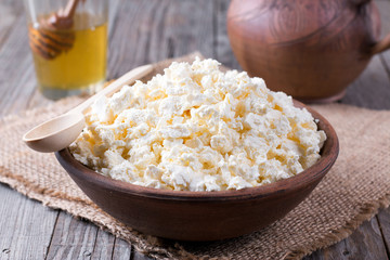 Homemade cottage cheese in a bowl on old wooden table