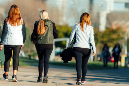 Three Women With Leggings Walking Down A Sidewalk