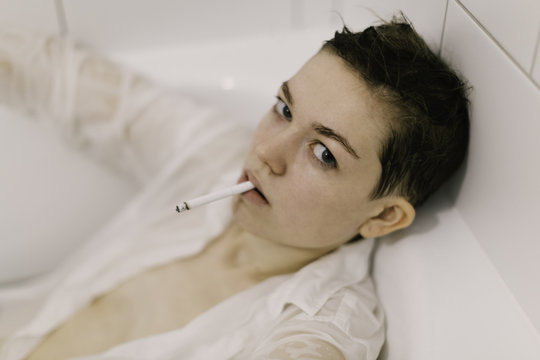 Young woman smoking in bathtub