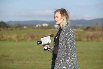 Side view of girl holding film camera.
