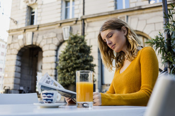 Woman reading newspaper in a bar