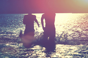 Glückliche junge Menschen laufen und springen am See beim Sonnenuntergang