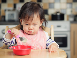 baby girl eating  yoghurt at home