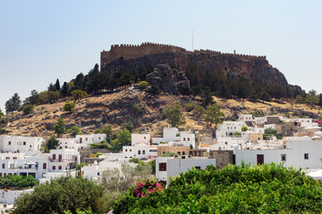 Obraz premium Panoramic view on Lindos town with an ancient fortress on a hill at Rhodes island, Greece