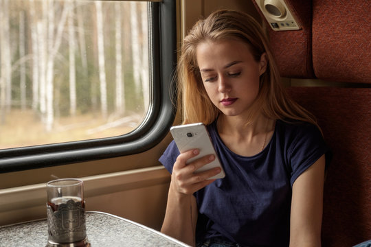 Calm blonde girl using mobile inside train