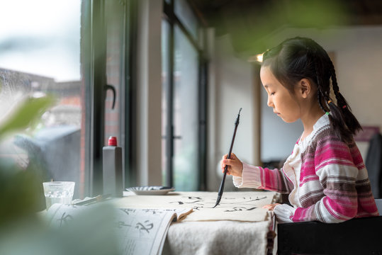Adorable little girl practicing calligraphy at home