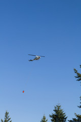 Aerial firefighting with helicopter carrying water bucket