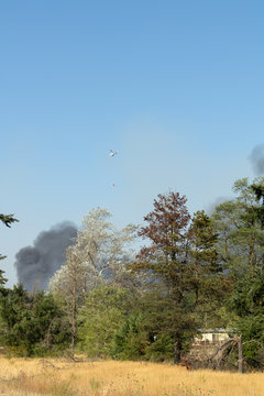 Helicopter fire fighting over brush fire and home