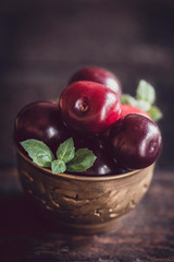 Group of cherries in the old metal cup on wooden background,selective focus