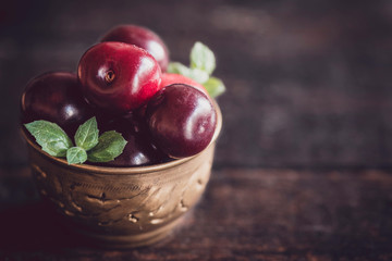 Group of cherries in the old metal cup on wooden background with blank space,selective focus