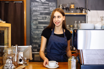 Young girl barista serves a cup of ready-made coffee