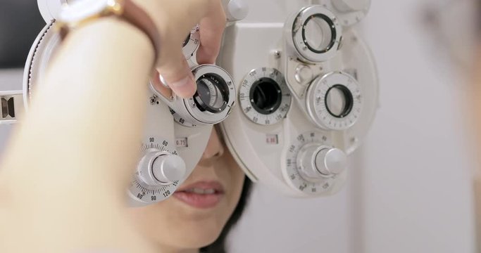Woman looking at eye test machine in ophthalmologist