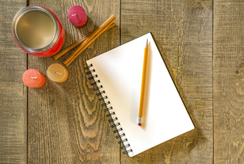 Rustic wooden table with blank white notebook and pencil, coffee in vintage thermos