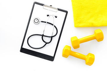 Sport and health. Fitness. Dumbbells and stethoscope on white background top view